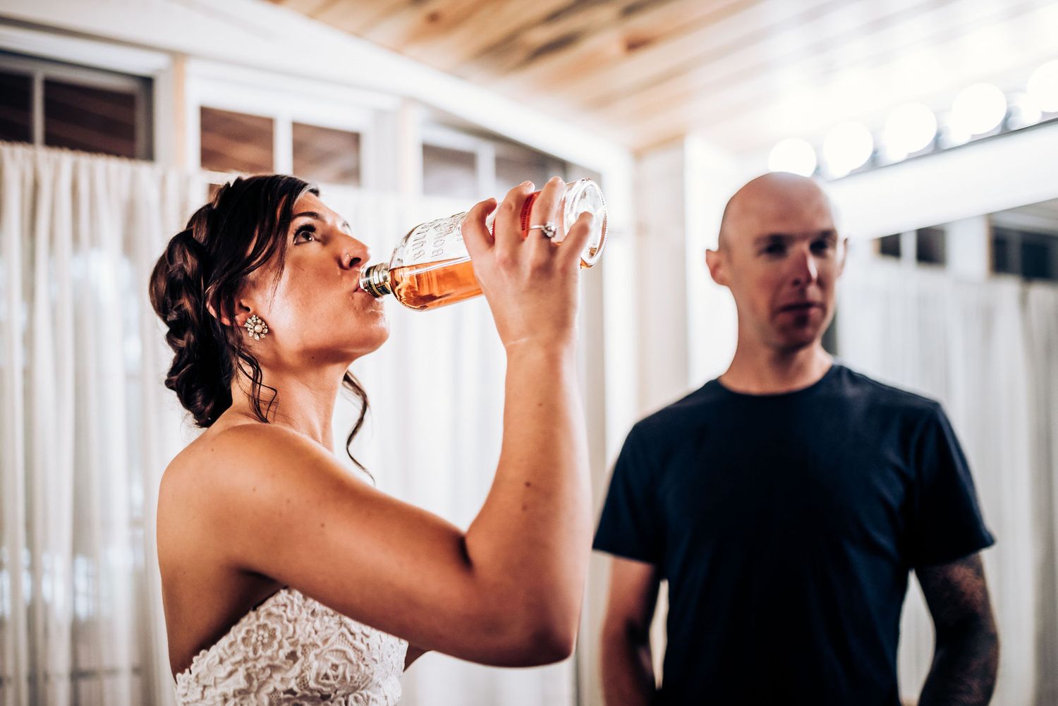 Bride in wedding dress taking a drink while getting ready.
