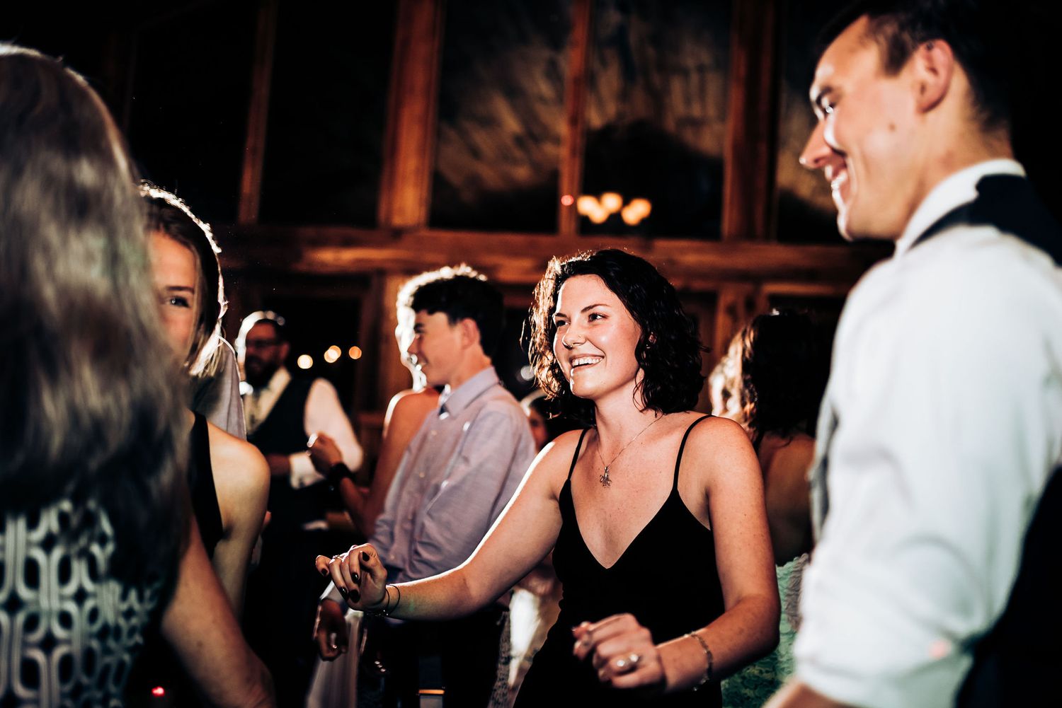 Wedding guests dancing and socializing at a dimly lit reception venue.