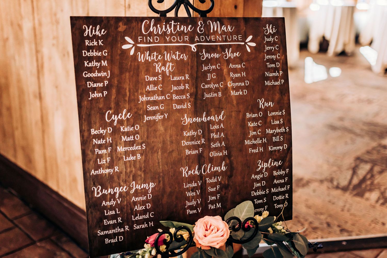 Rustic wooden seating chart display decorated with floral accents for a wedding.