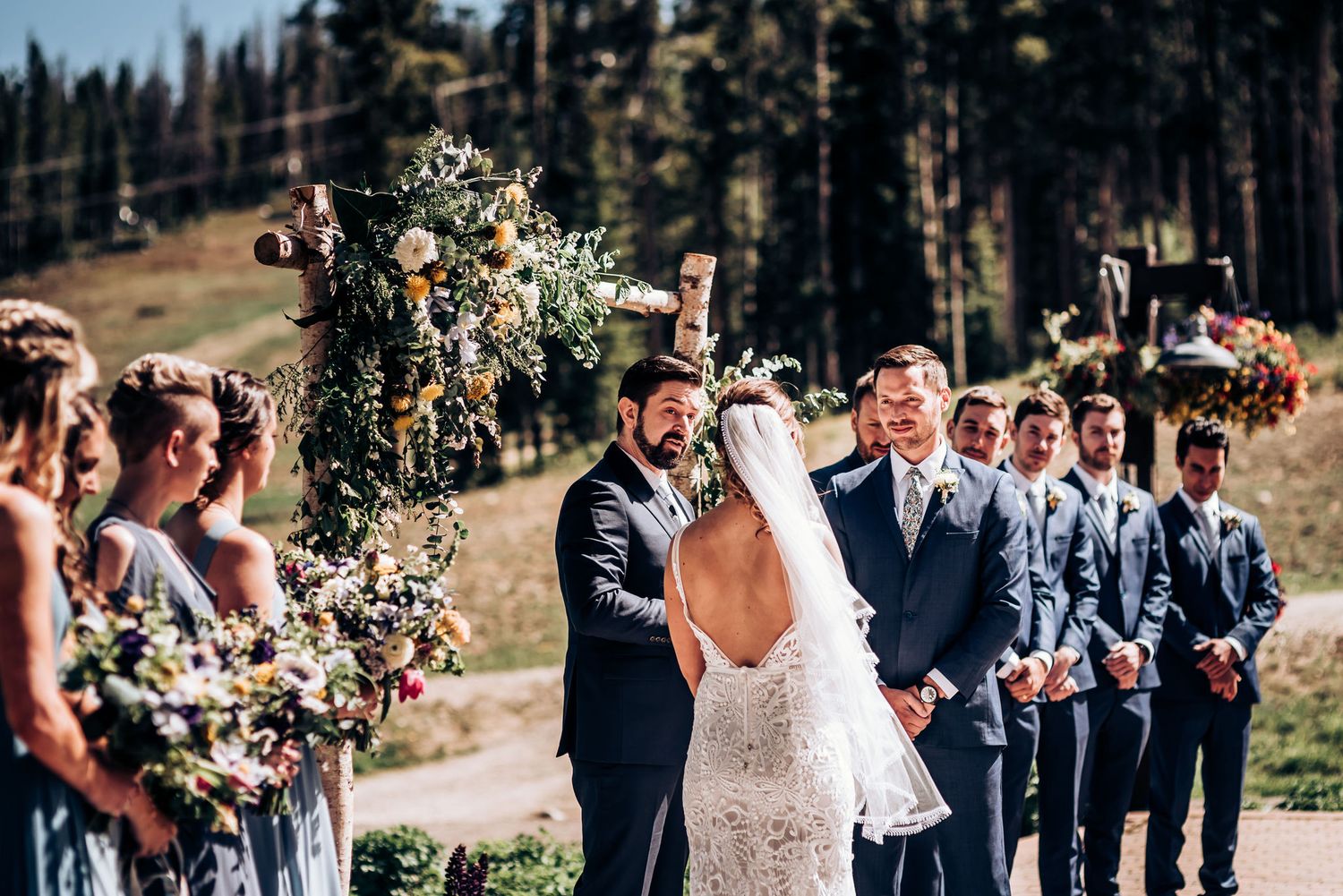 Outdoor wedding ceremony with mountain backdrop and floral decorations.