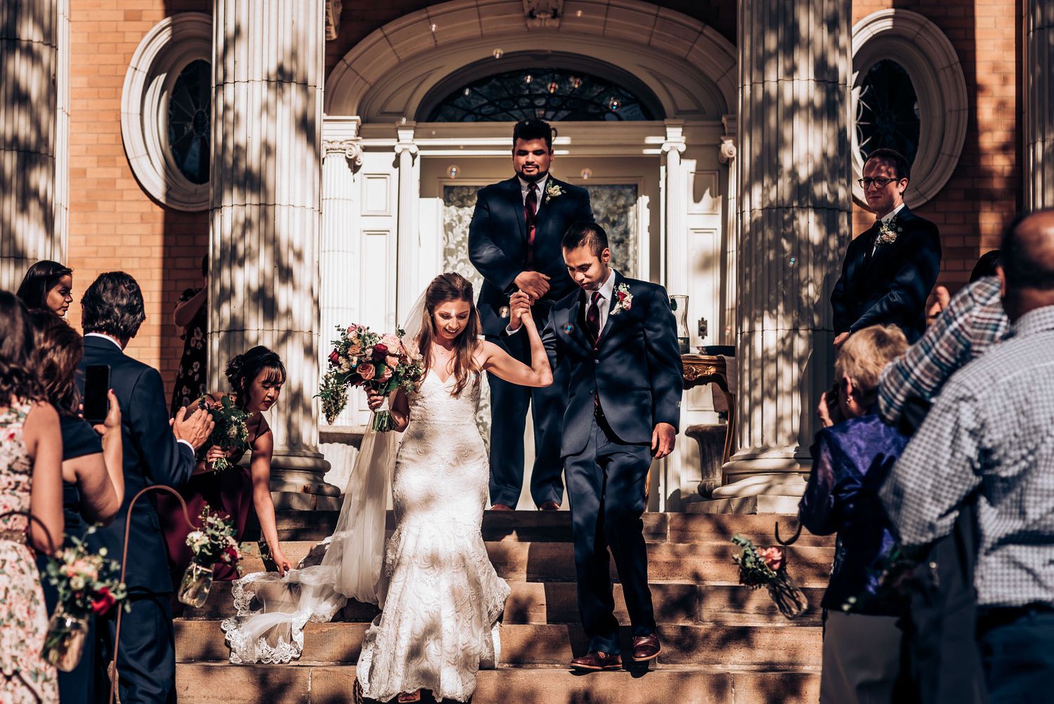 Wedding celebration on grand building steps with confetti being thrown by guests.