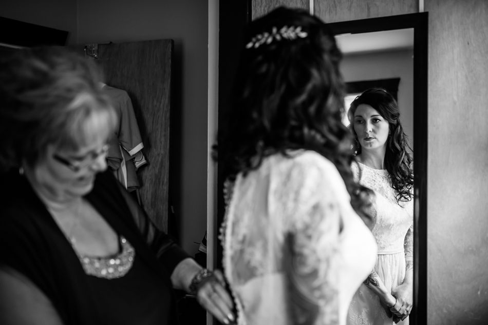 Black and white reflection of bridal preparation in mirror with vintage styling.