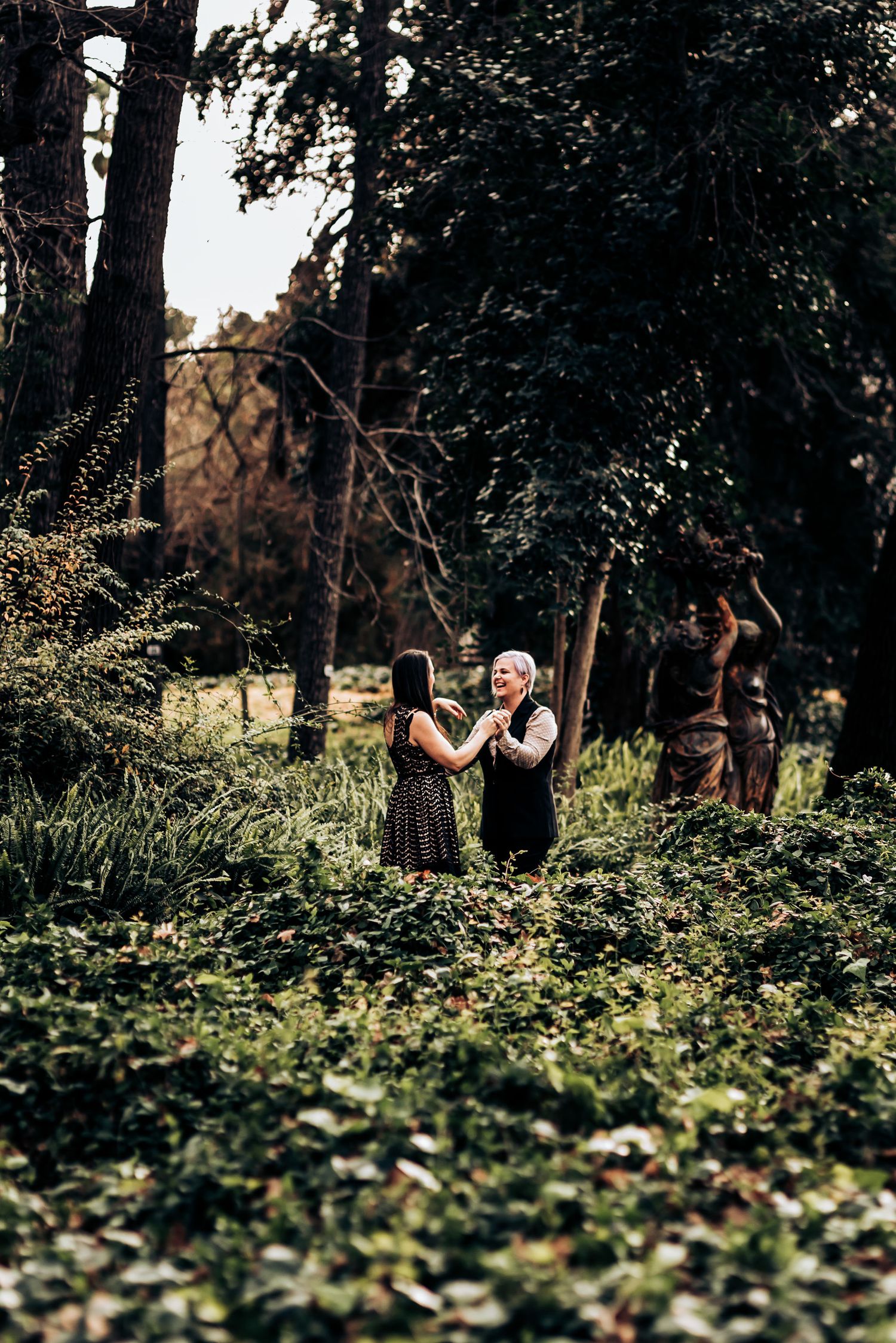 Intimate moment captured in wooded garden setting with natural greenery surrounding.