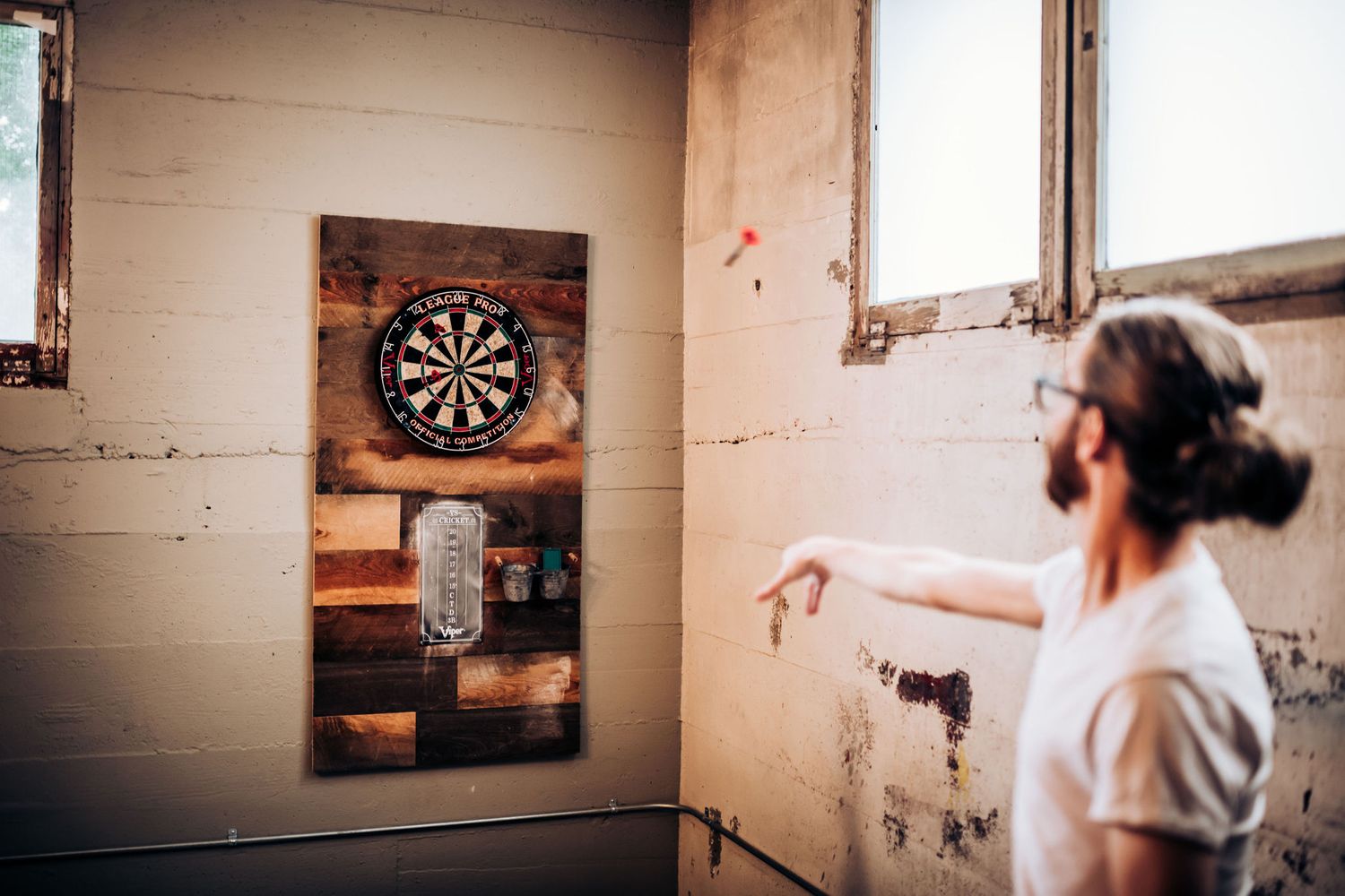 Person playing darts in an industrial-style room with vintage aesthetic.