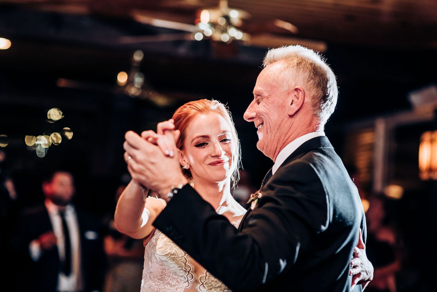 A couple dances together while smiling during their wedding celebration.