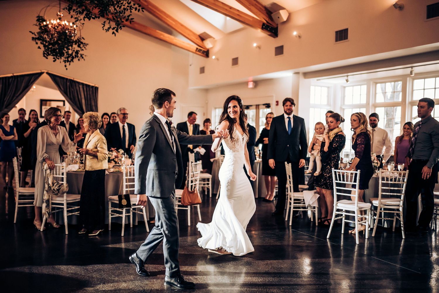 Wedding reception celebratory moment in elegant venue with exposed wooden beams.