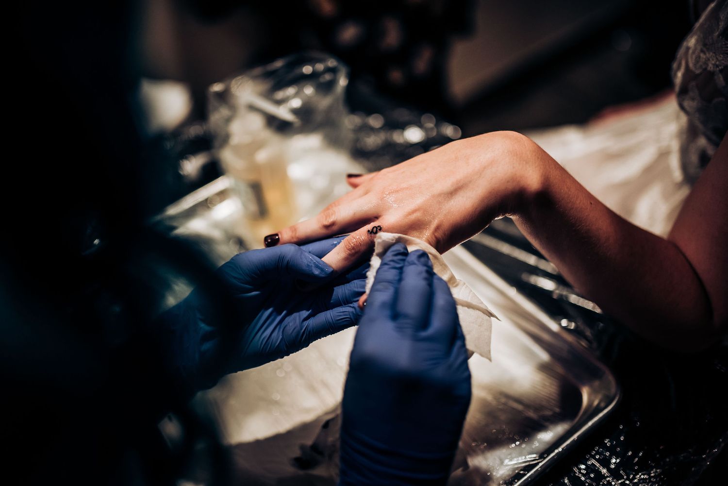 Close-up of hands wearing blue gloves working on a detailed design at an event.
