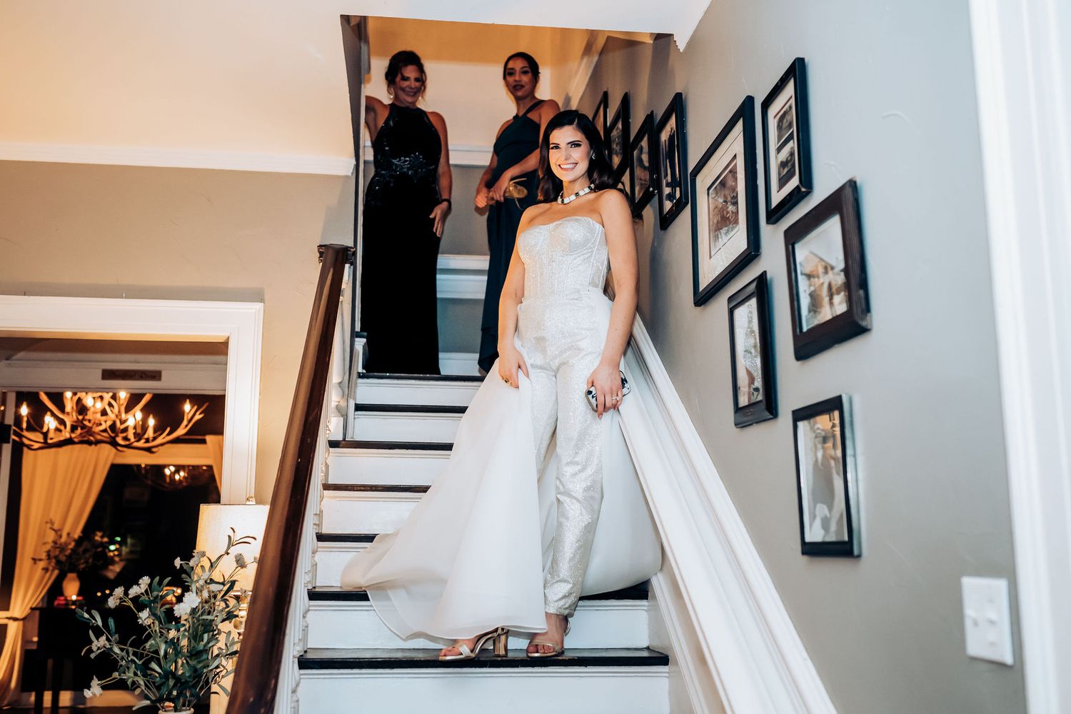 Wedding preparations on white staircase with framed photos on wall.