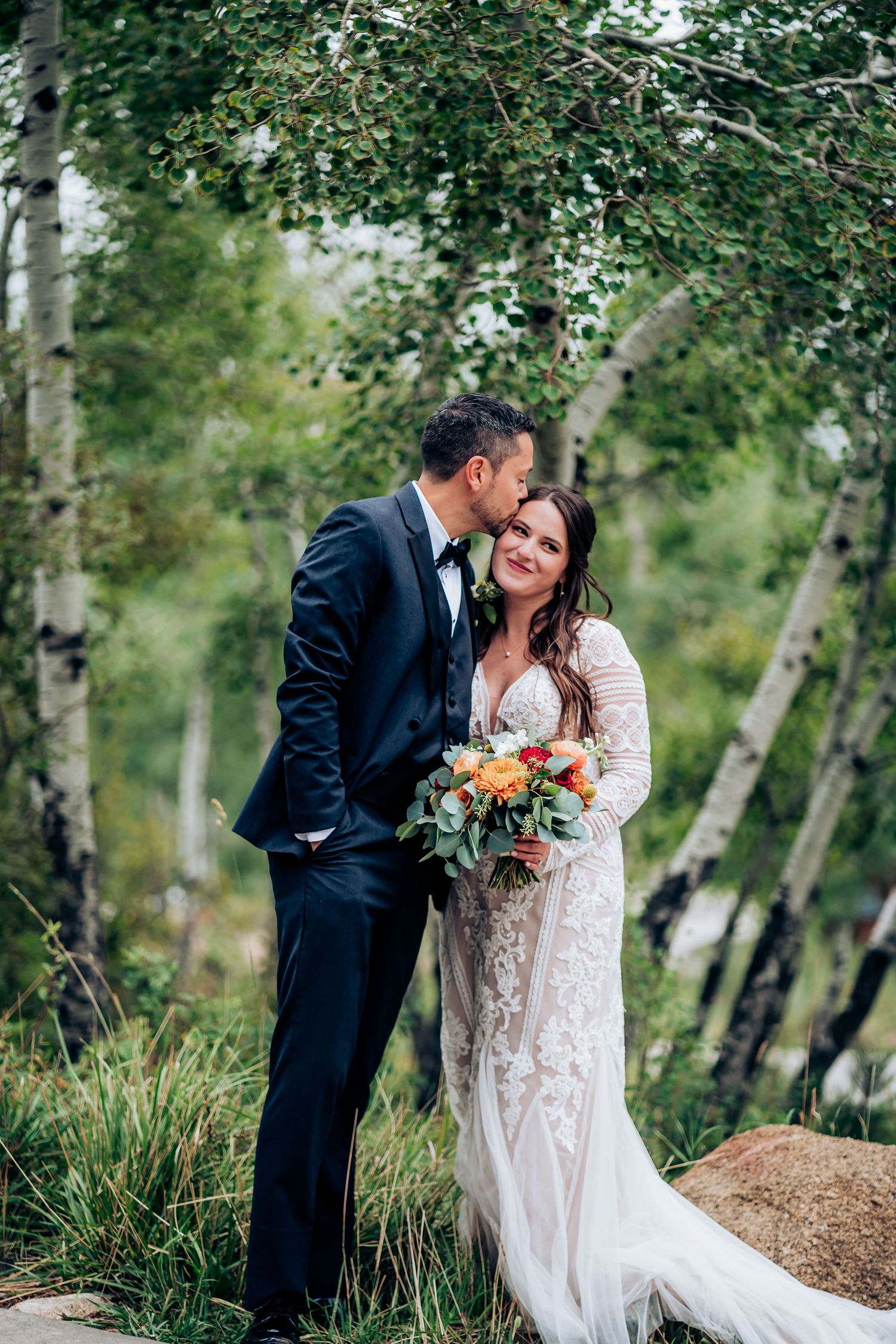 A couple shares an intimate moment among aspen trees during their wedding portraits.