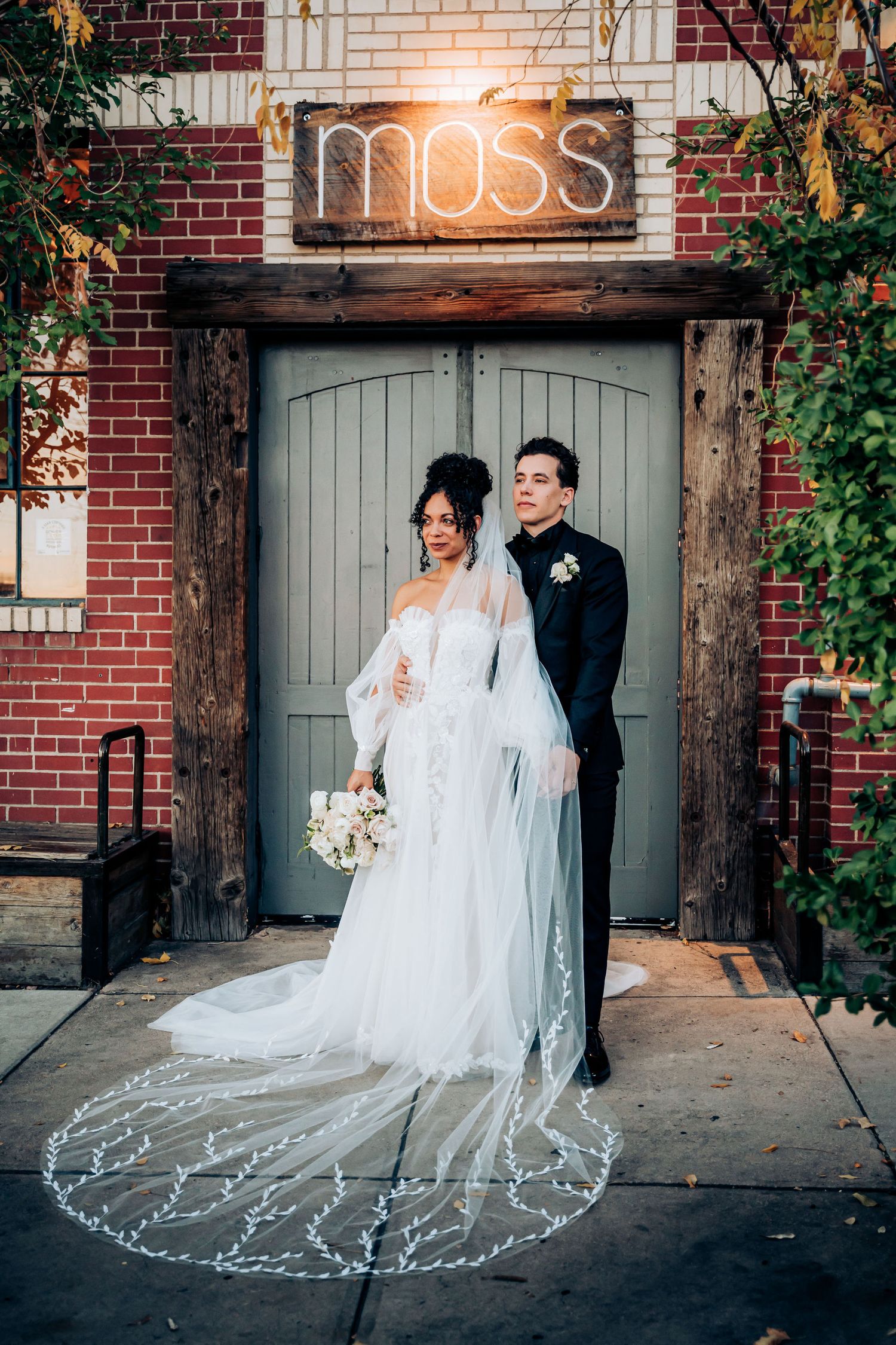 Wedding portrait in front of Moss venue featuring a stunning long veil and gray double doors.