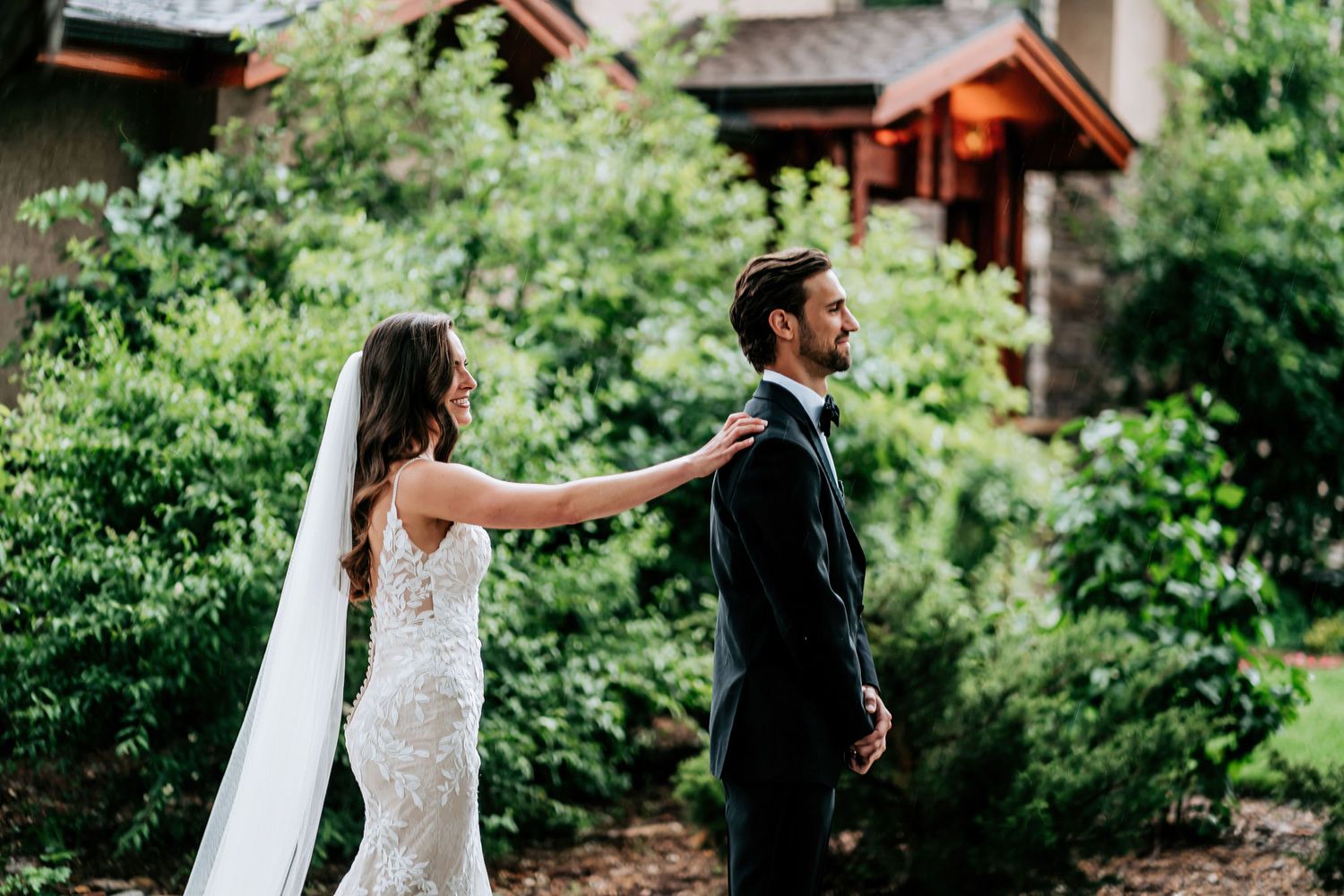 First look moment between wedding couple in a garden setting with lush greenery.