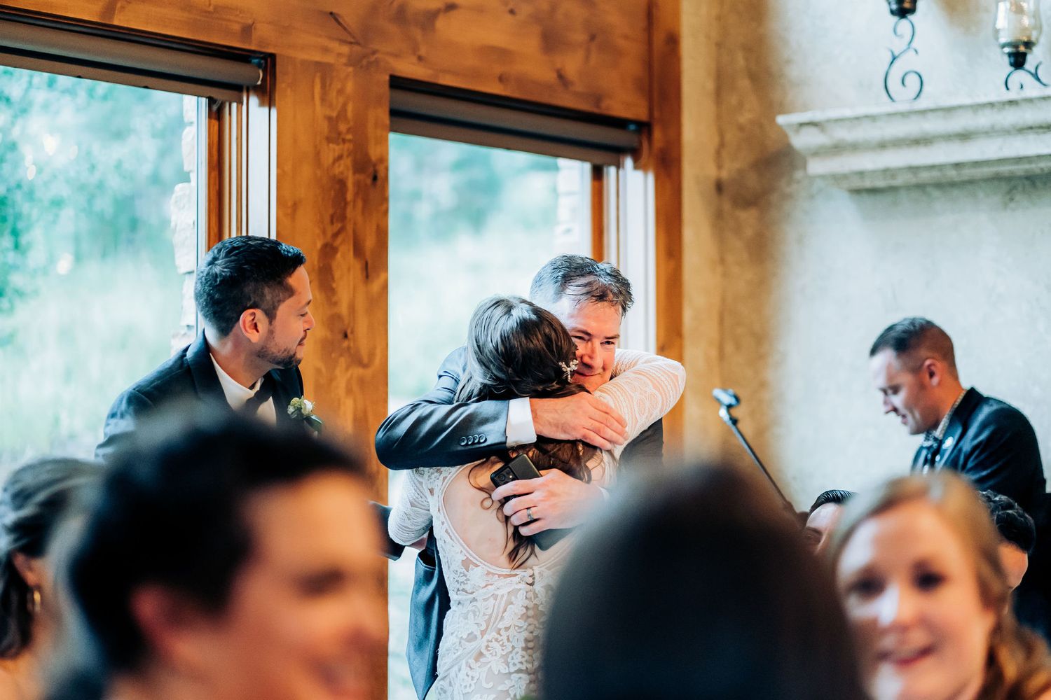 Emotional moment captured during wedding reception with warm wooden interior and natural lighting.