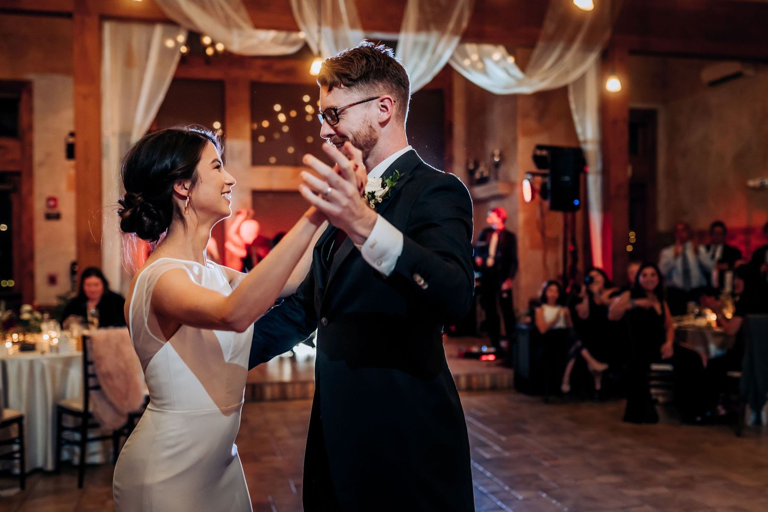 A couple dancing together during their wedding reception in an elegantly lit venue.