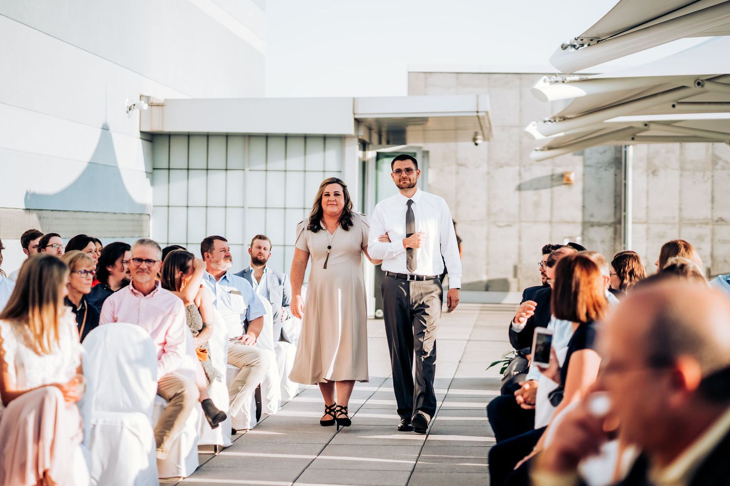 Wedding ceremony processional on modern white architectural terrace.