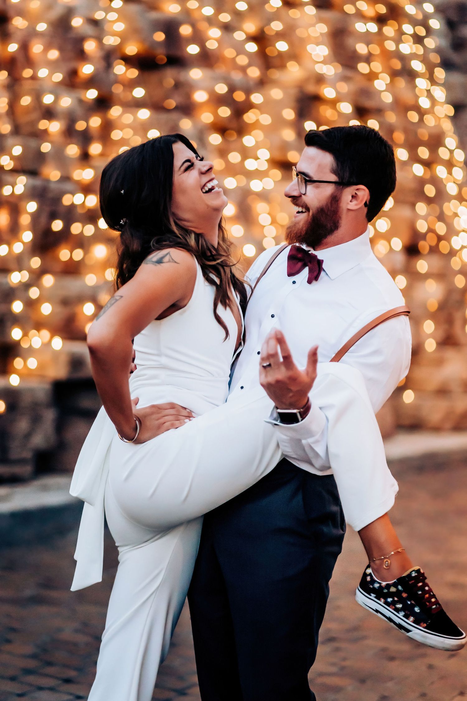 A joyful couple shares a romantic moment against a backdrop of warm twinkling lights.