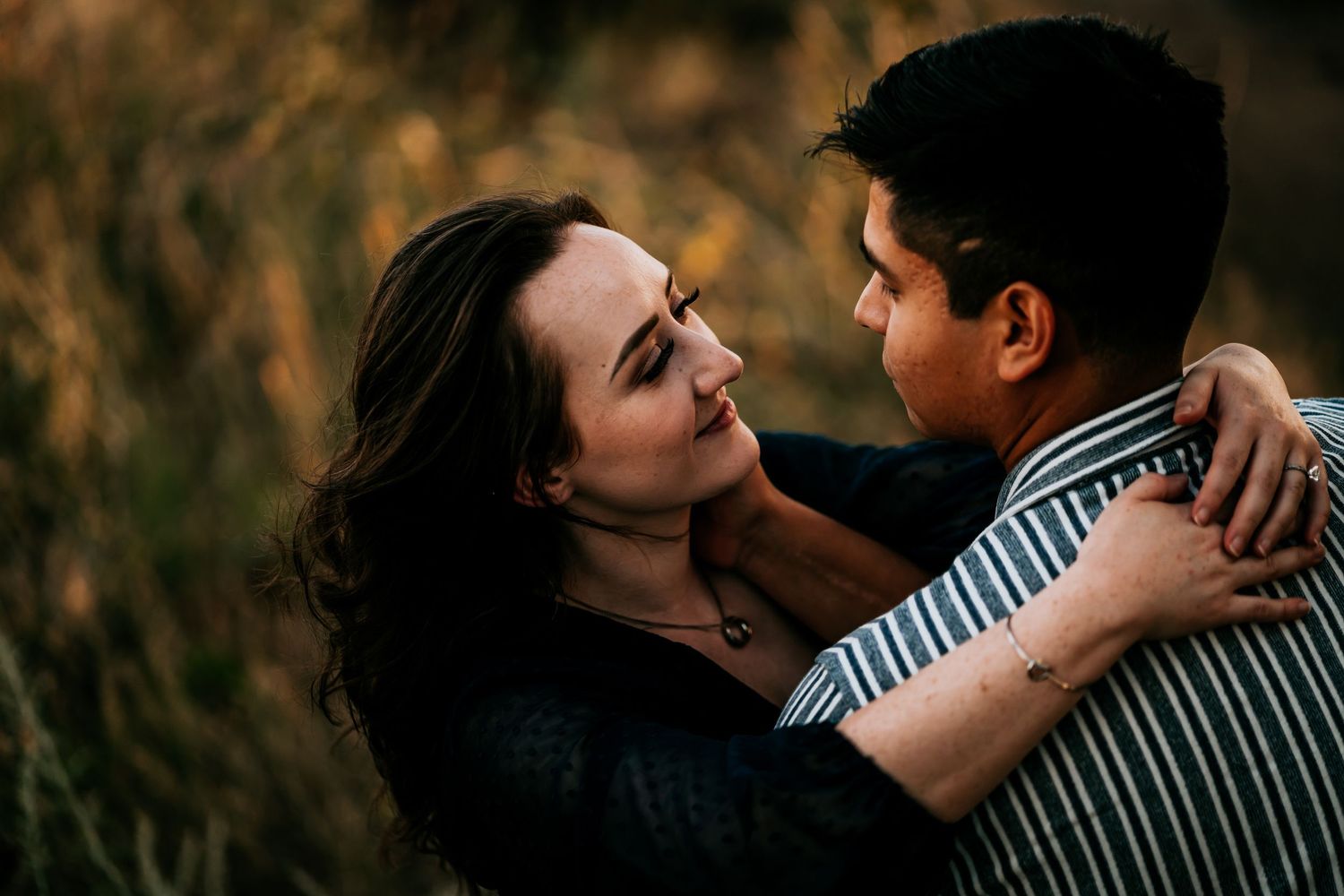 A romantic couple shares an intimate moment at sunset in a natural setting.