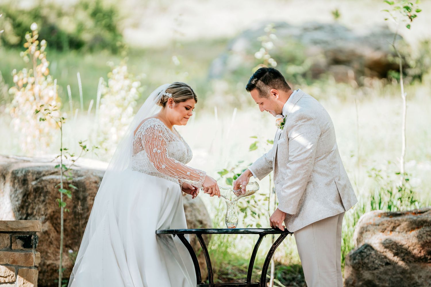 Couple in wedding attire sharing an intimate moment at a decorated outdoor table.