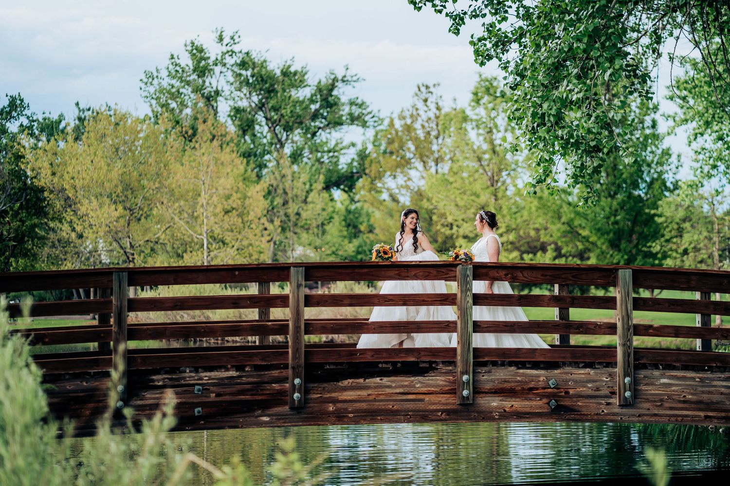Romantic wedding photo on wooden bridge over water with natural scenery.