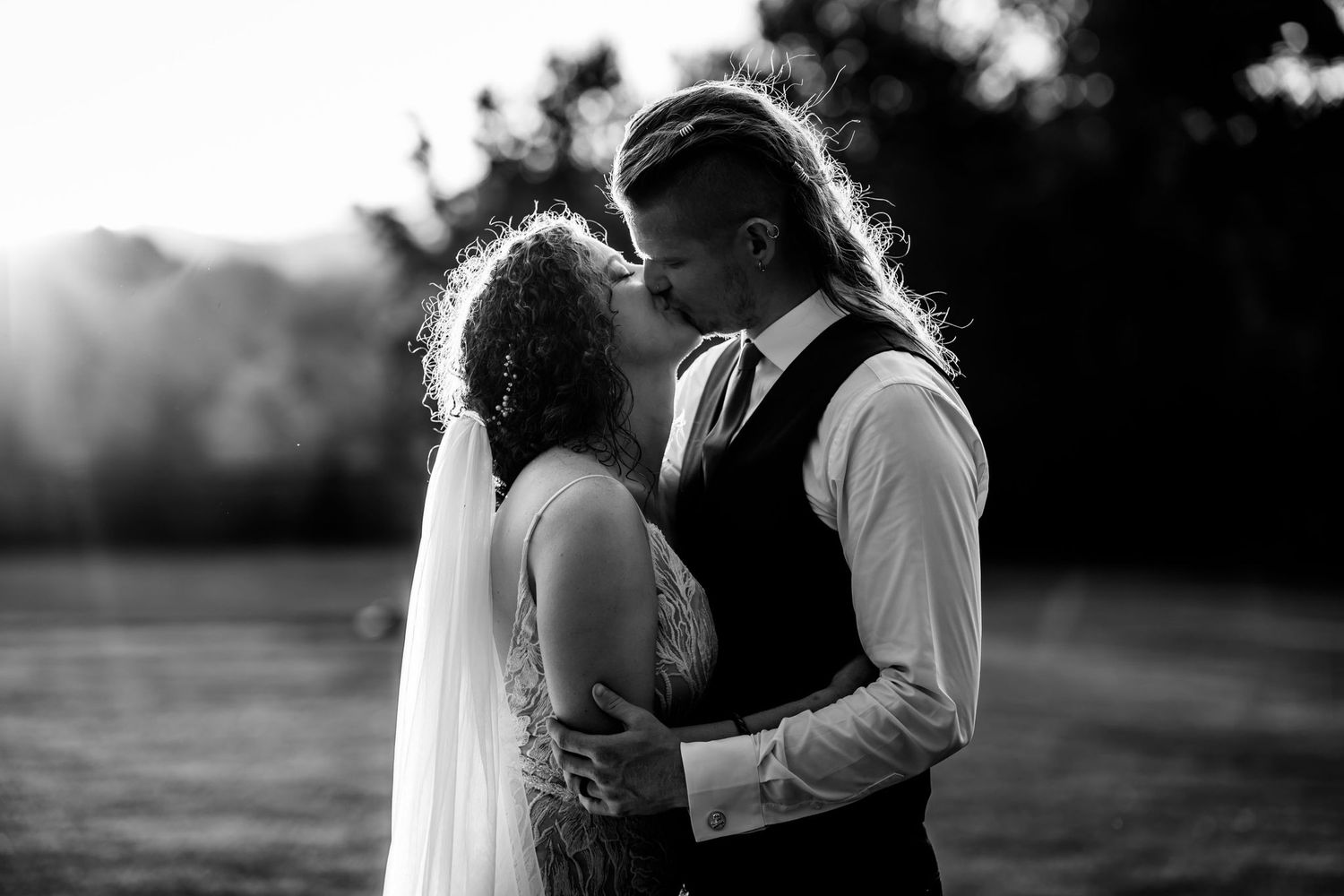 Black and white portrait of couple embracing in romantic sunset moment.