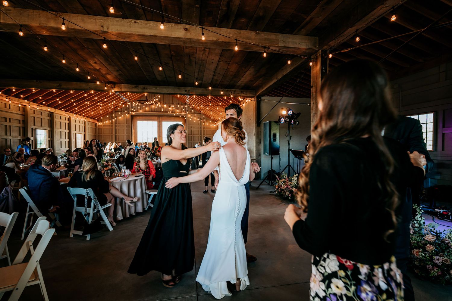 Wedding celebration in industrial-style venue with string lights and folding chairs.