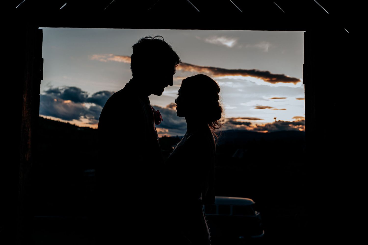 A silhouetted couple stands together against a dramatic sunset sky.