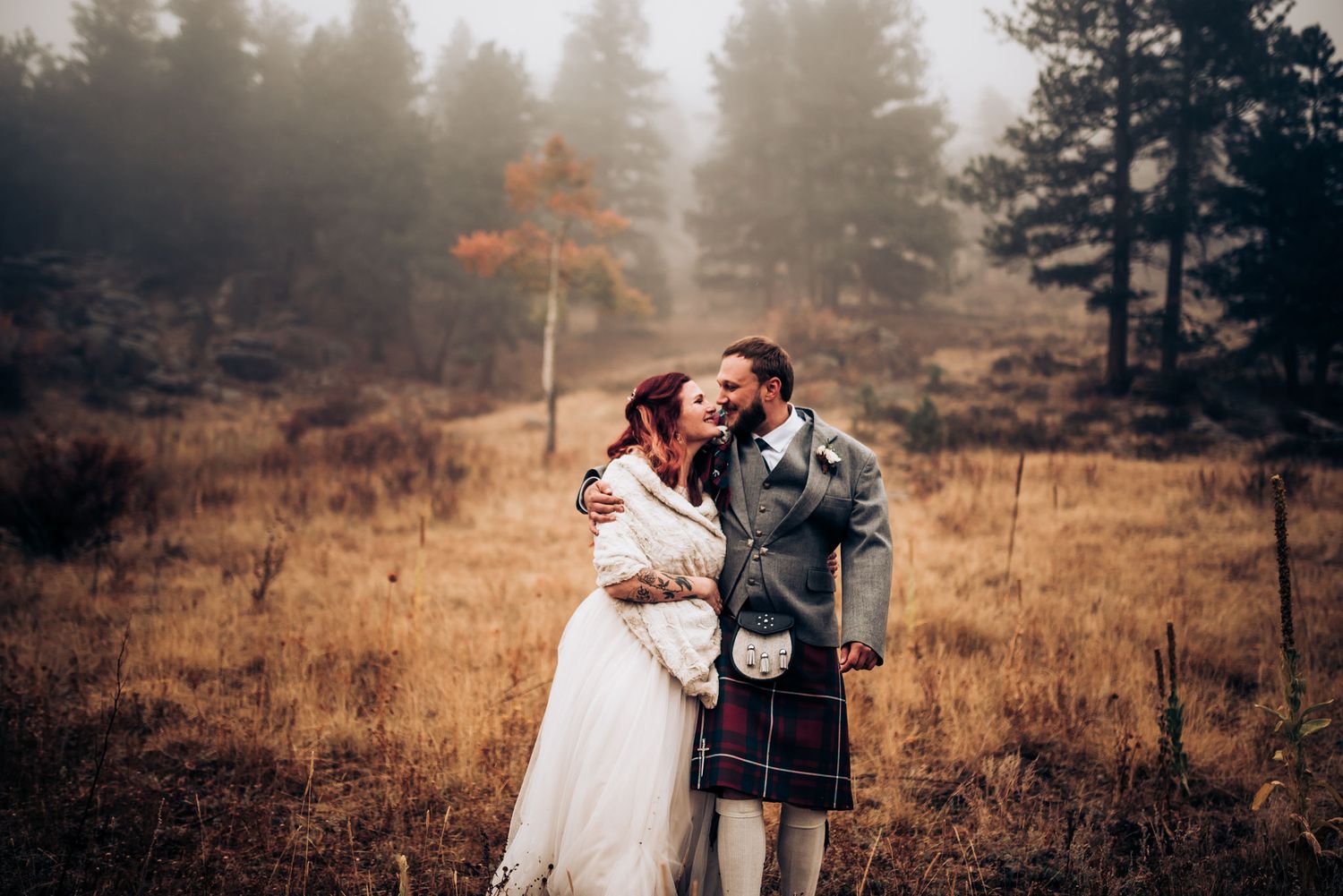 Scottish highland wedding scene with traditional dress against misty forest backdrop.