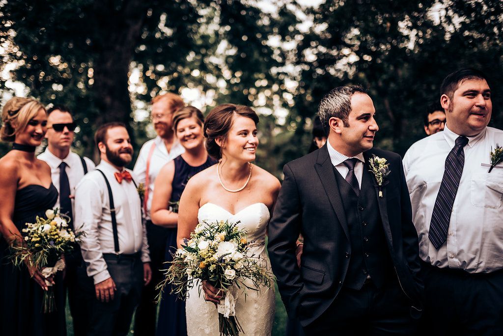 Candid outdoor wedding photo with wedding party members laughing together.