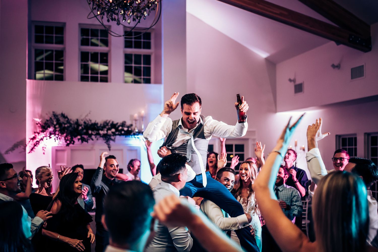 Energetic party scene with crowd surfing during a wedding reception.