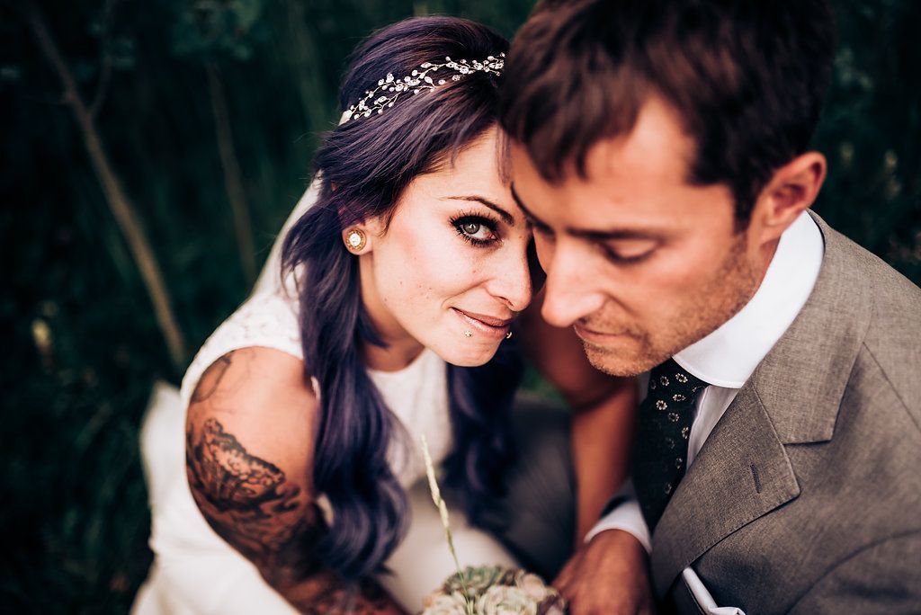 Intimate wedding portrait with soft natural lighting and greenery background.