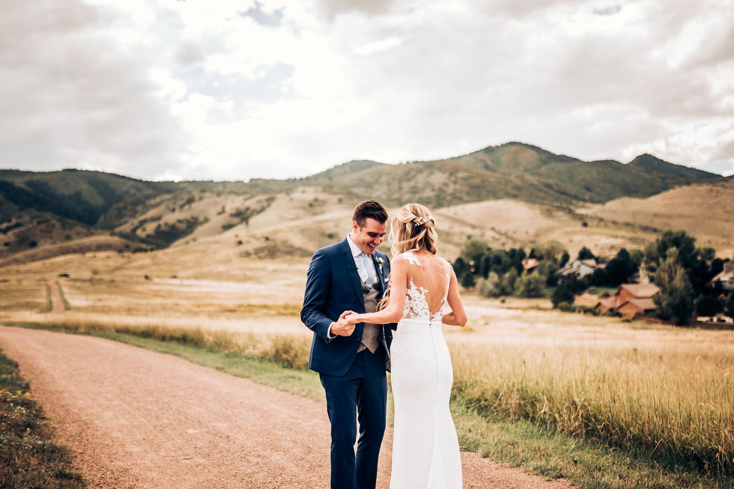 Wedding couple shares intimate moment on mountain path with dramatic landscape behind them.