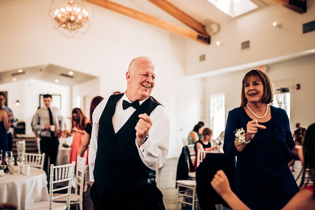 Wedding guests dancing and celebrating with joy at an elegant indoor reception venue.