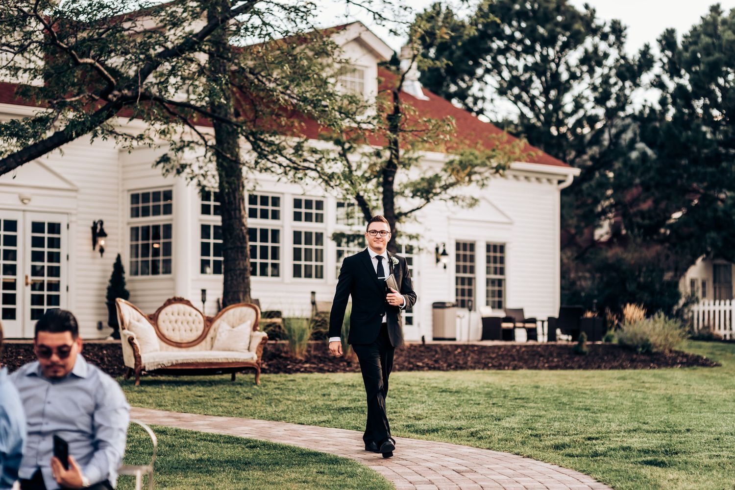 Person walking along stone pathway outside elegant white colonial building.