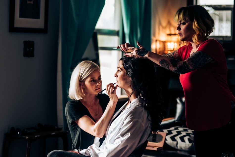 Behind-the-scenes preparation with stylists working on hair and makeup.
