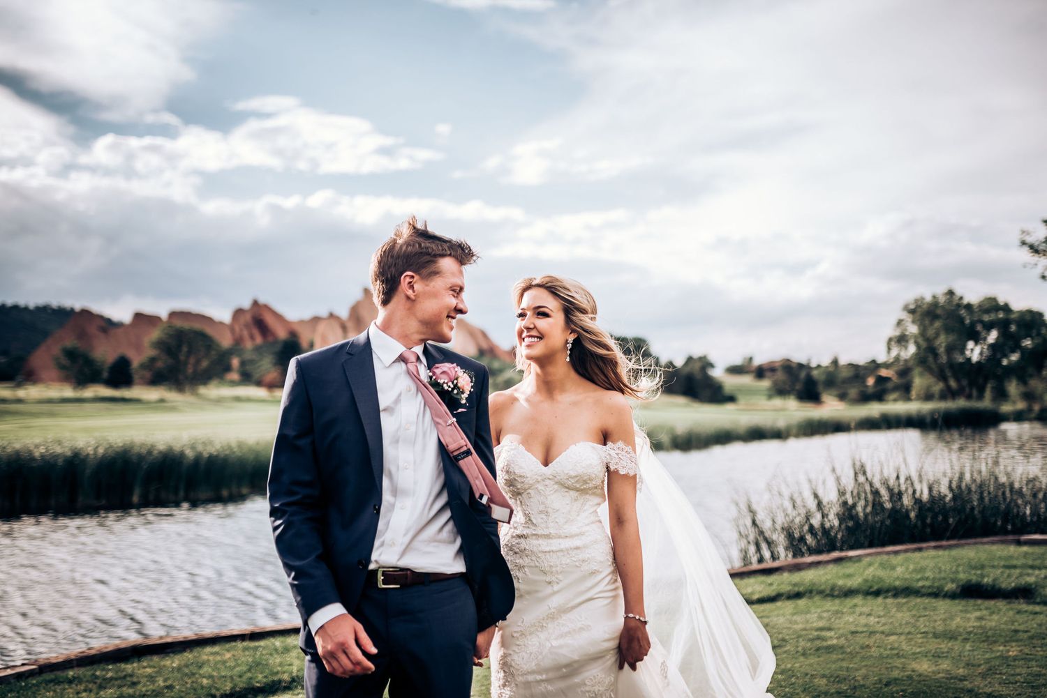 Candid wedding moment captured by lake with scenic mountain landscape.