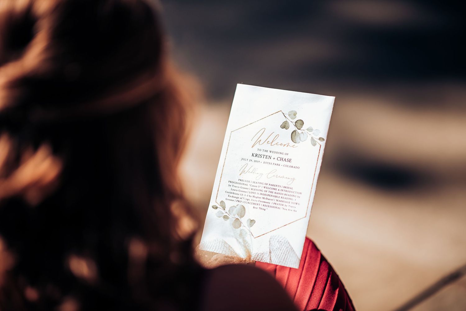 A wedding invitation being held against a blurred background with delicate floral details.