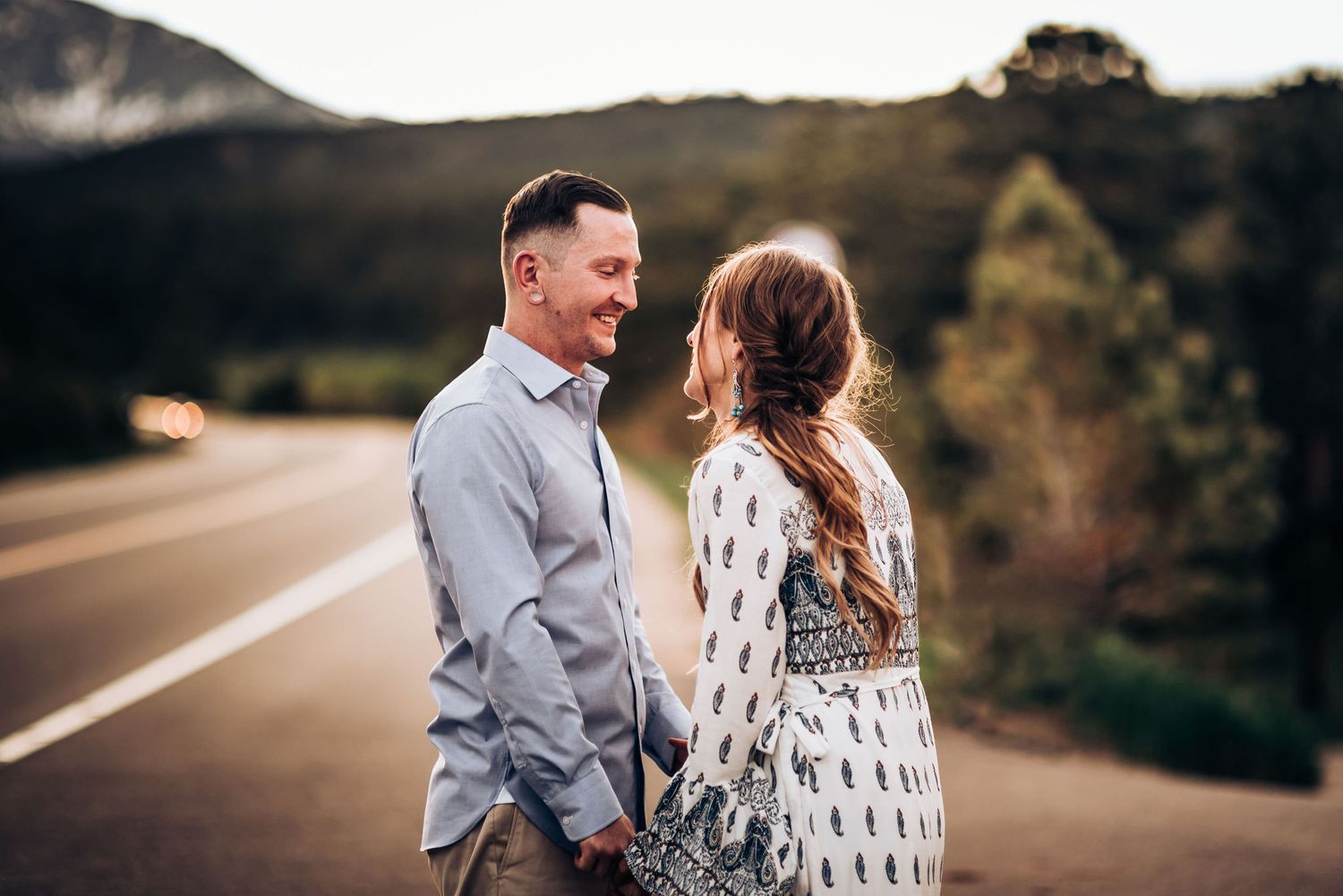 A couple shares an intimate moment on a mountain road during their sunset photoshoot.