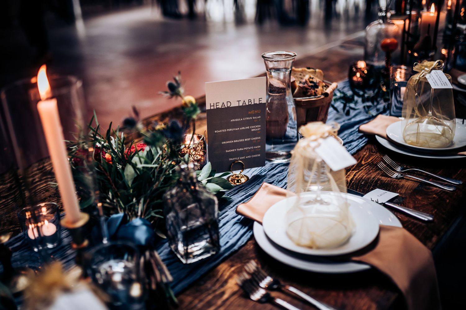 Rustic wedding table setting with candlelight, floral arrangements and place settings.
