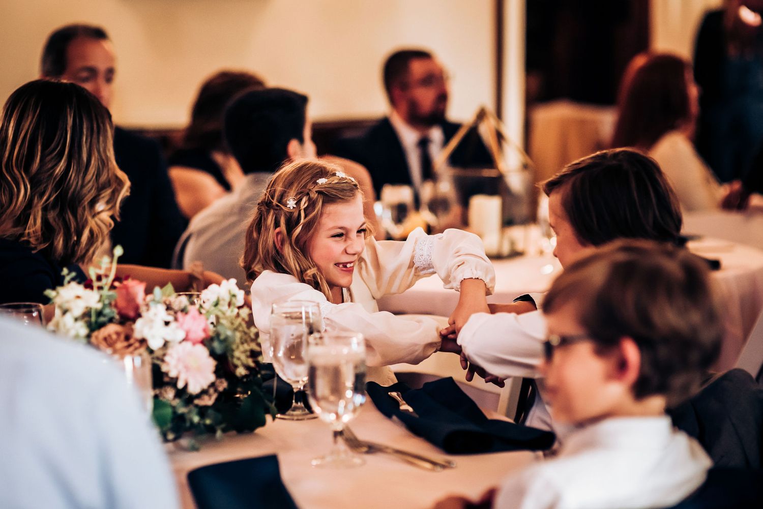 Wedding reception guests enjoying conversation and laughter at decorated dining table.
