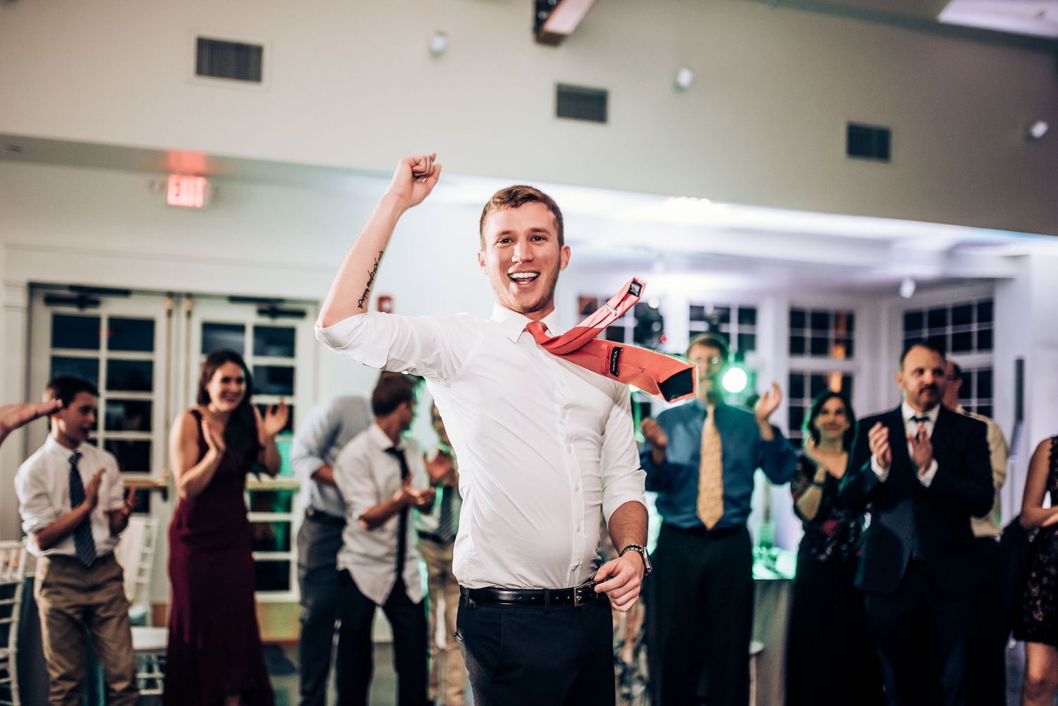 Celebratory moment at wedding reception as guest raises arms in victory pose.