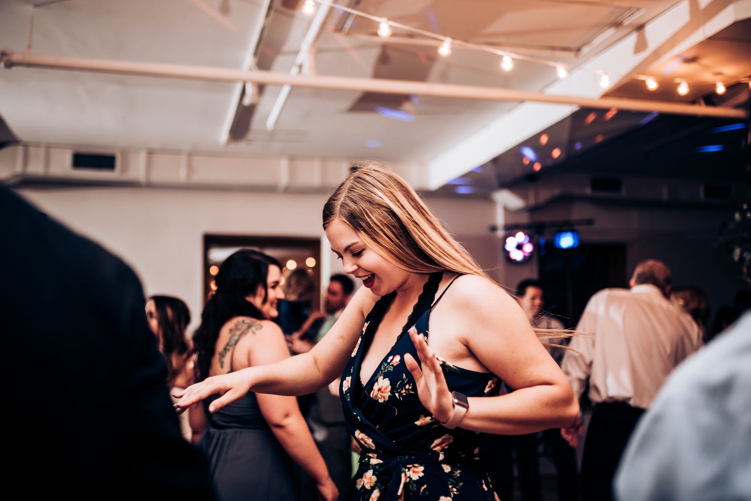 Partygoers dance enthusiastically at a reception under atmospheric lighting.