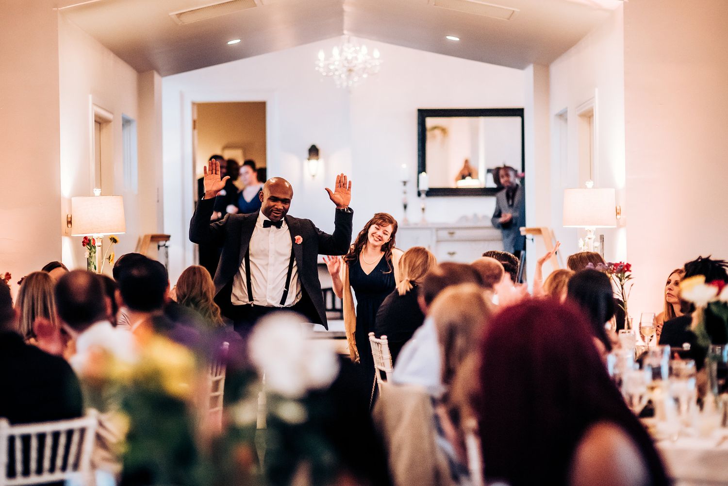 Lively wedding reception scene with guests mingling at decorated tables.