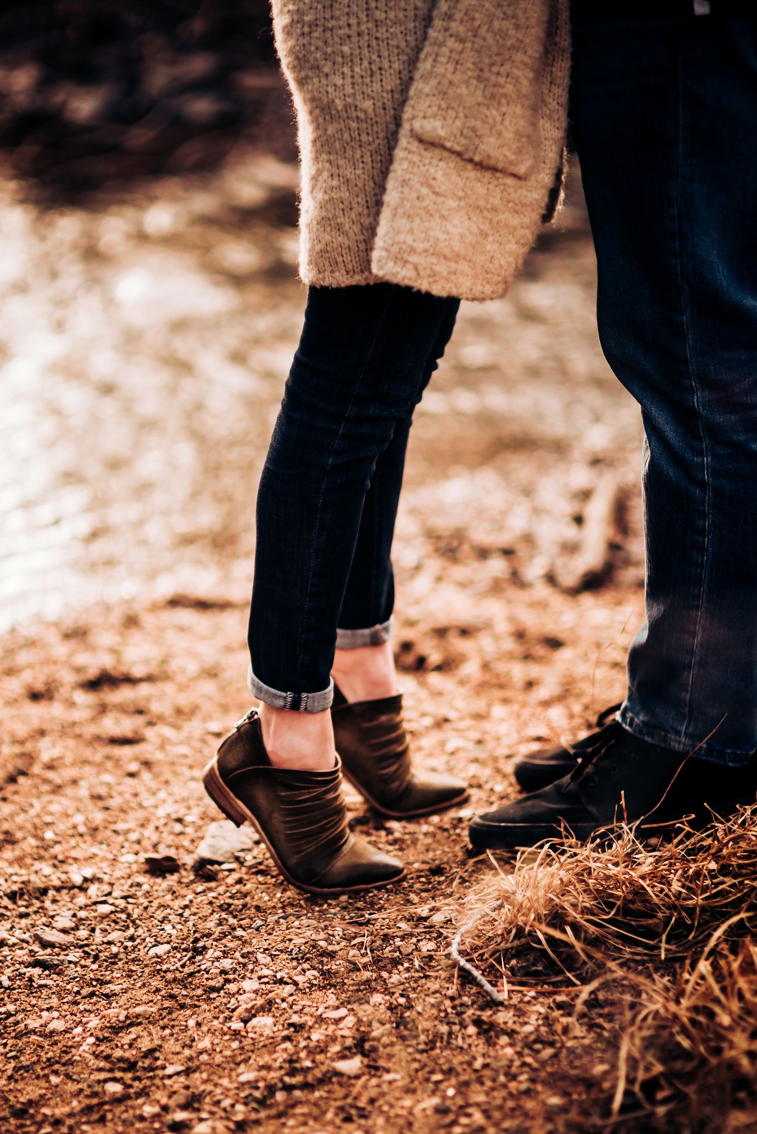 Close-up of couple's feet standing together on fallen autumn leaves.