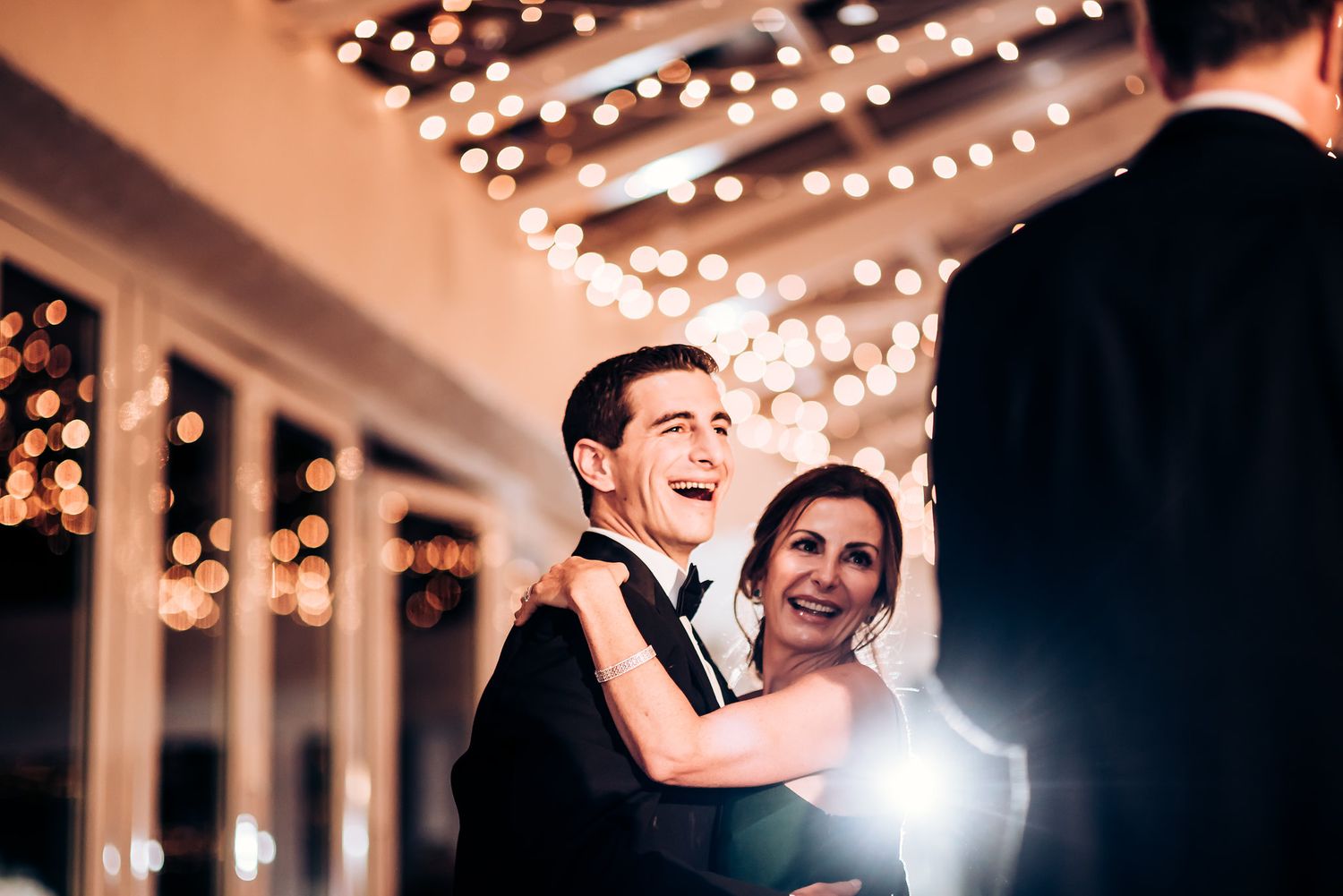 Wedding reception couple shares joyful dance moment under sparkling light display.