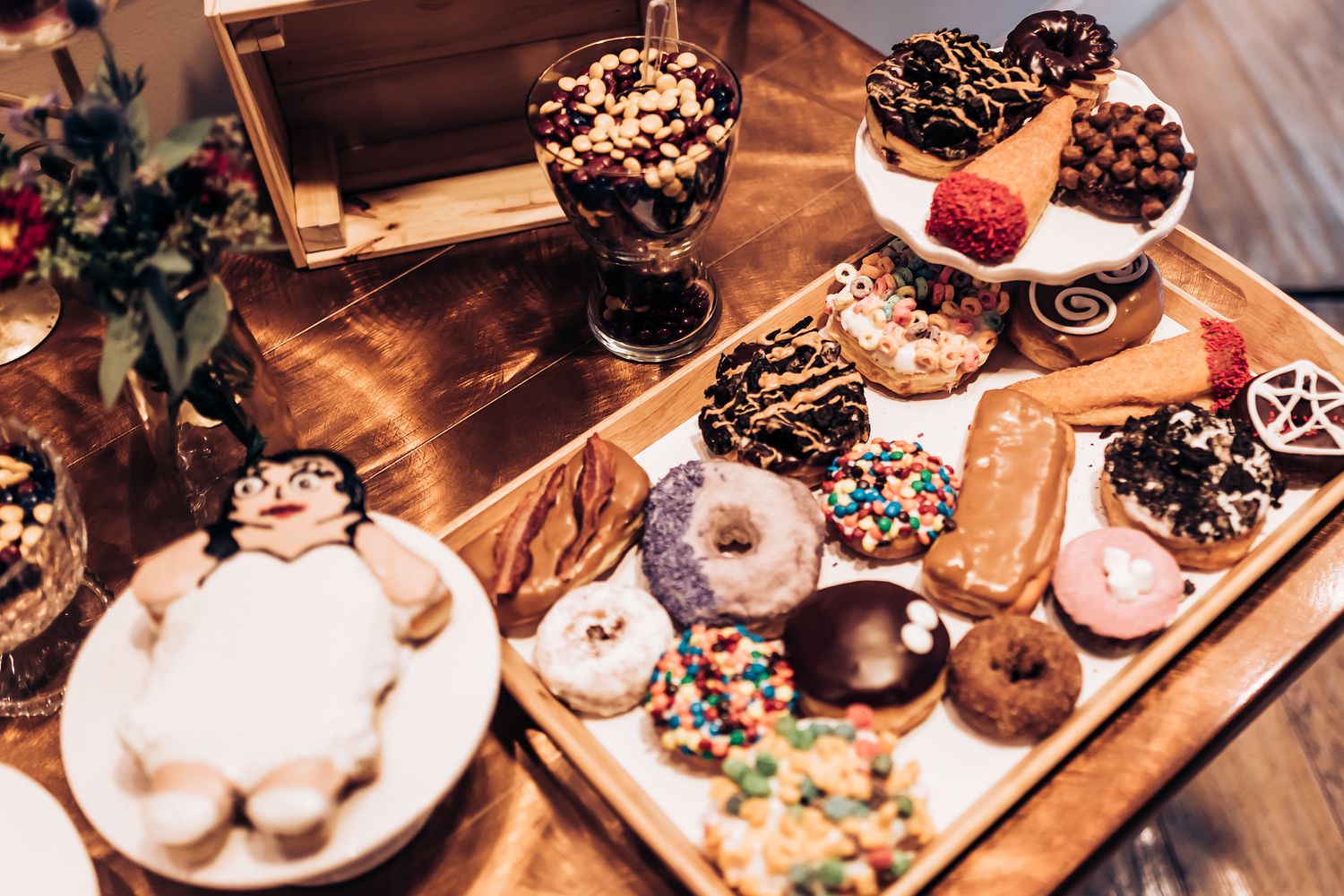 Assorted donuts and pastries displayed on wooden serving trays at wedding dessert table.