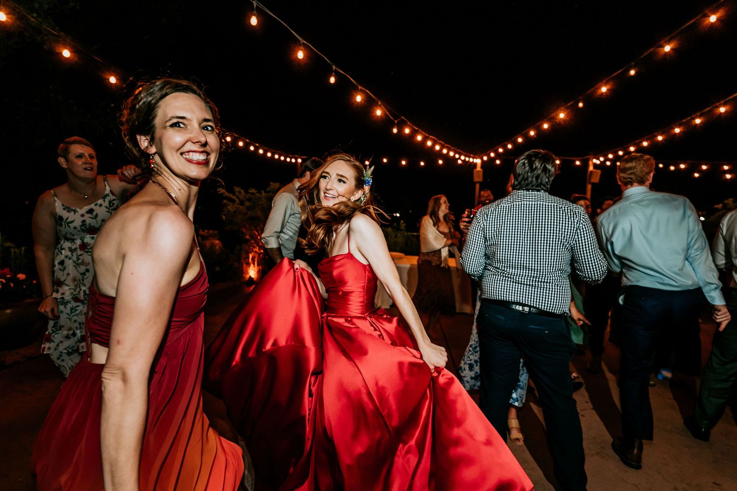 People dancing under string lights at an evening outdoor celebration.