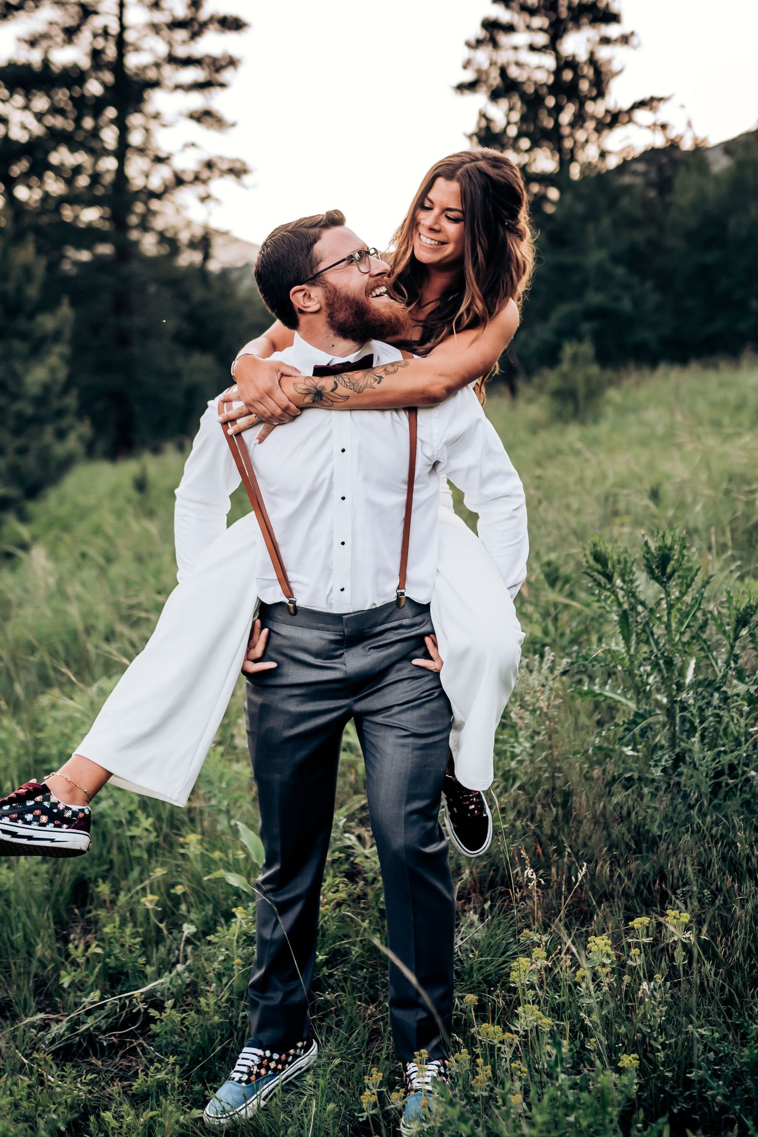 Joyful piggyback moment in a mountain meadow with pine trees in the background.