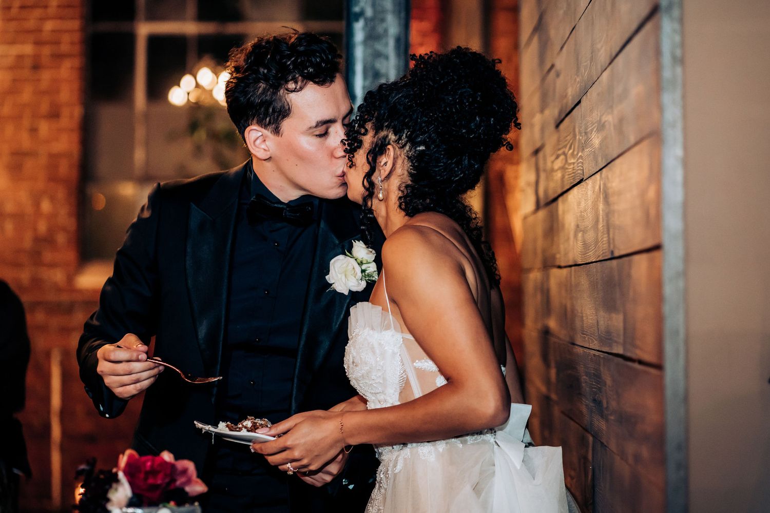 A tender wedding moment between newlyweds sharing food at their reception.