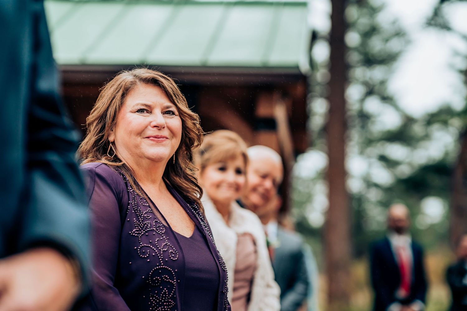 Guests sharing joyful moments during an outdoor wedding celebration in a wooded setting.
