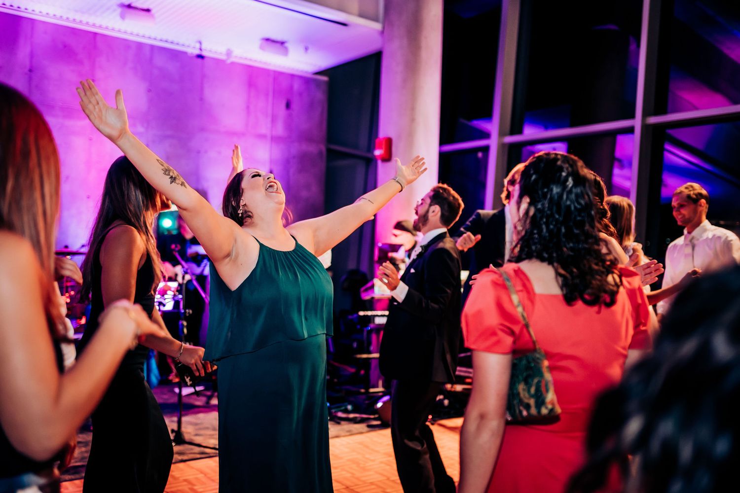 Guests dancing and having fun at a lively wedding reception with colorful mood lighting.