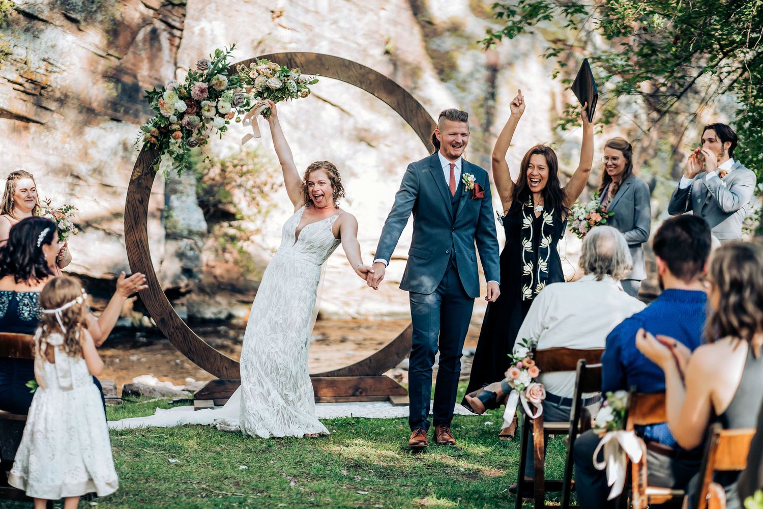 Joyful wedding celebration with circular arch and natural stone backdrop during outdoor ceremony.